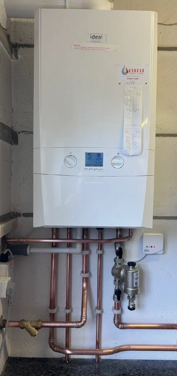 Ideal boiler mounted on a garage wall above a run of new copper pipework, an Ideal magnetic system filter and an EPH wireless receiver