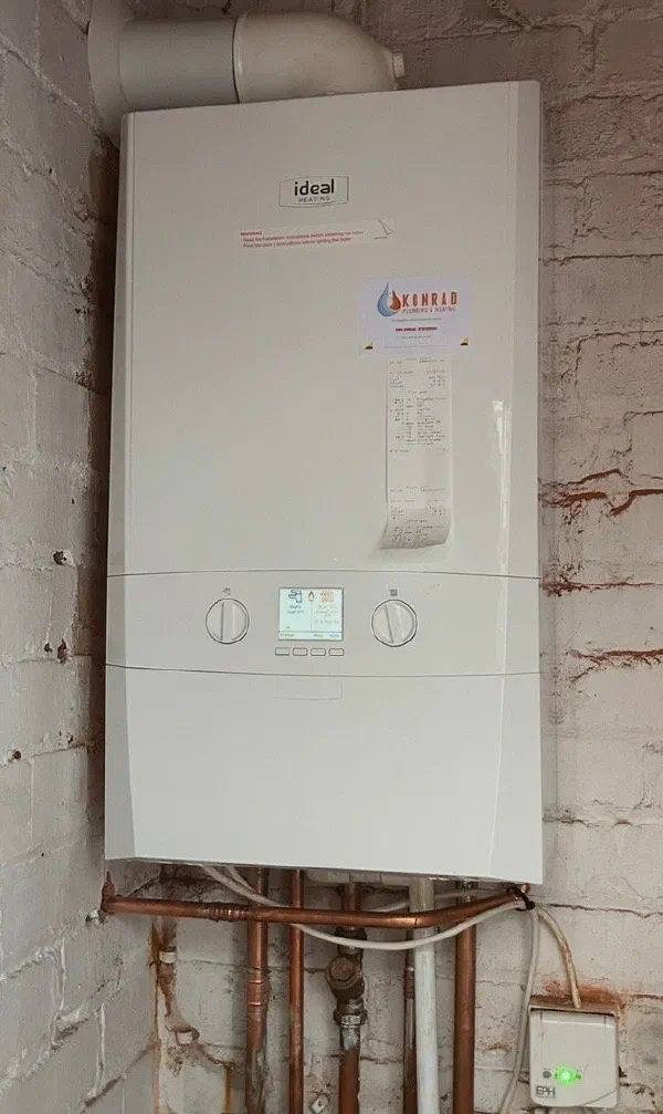 Ideal boiler installed on a whitewashed brick wall, with copper pipework below and an EPH heating control alongside